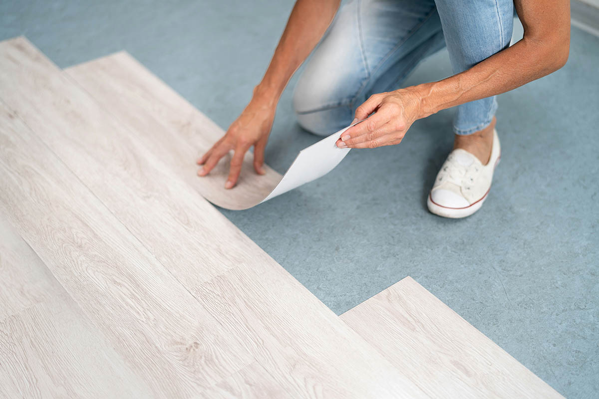 Professional installer laying vinyl flooring in a high-traffic area of a home or commercial space.